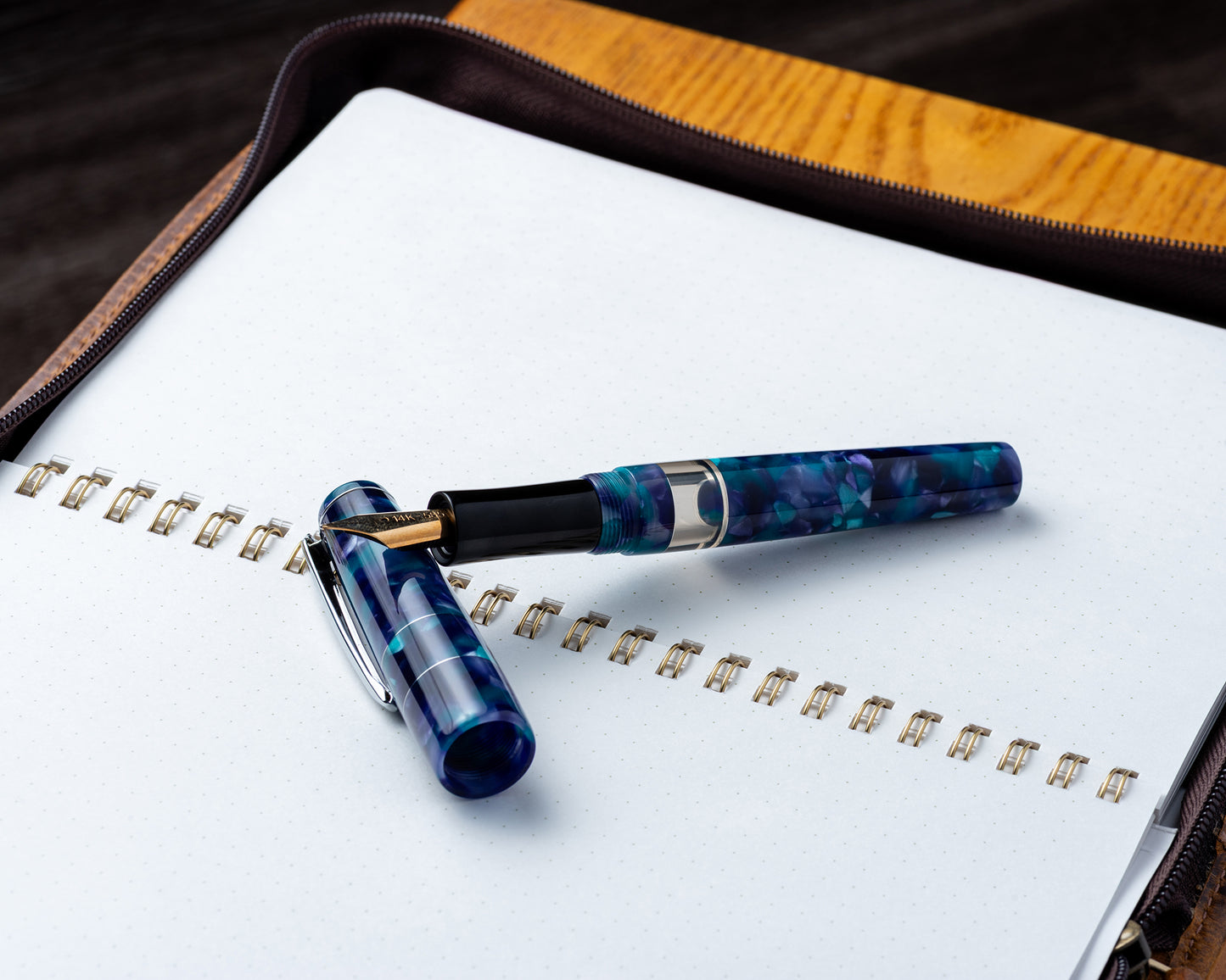 Blue and black pen on a notebook with a wooden surface