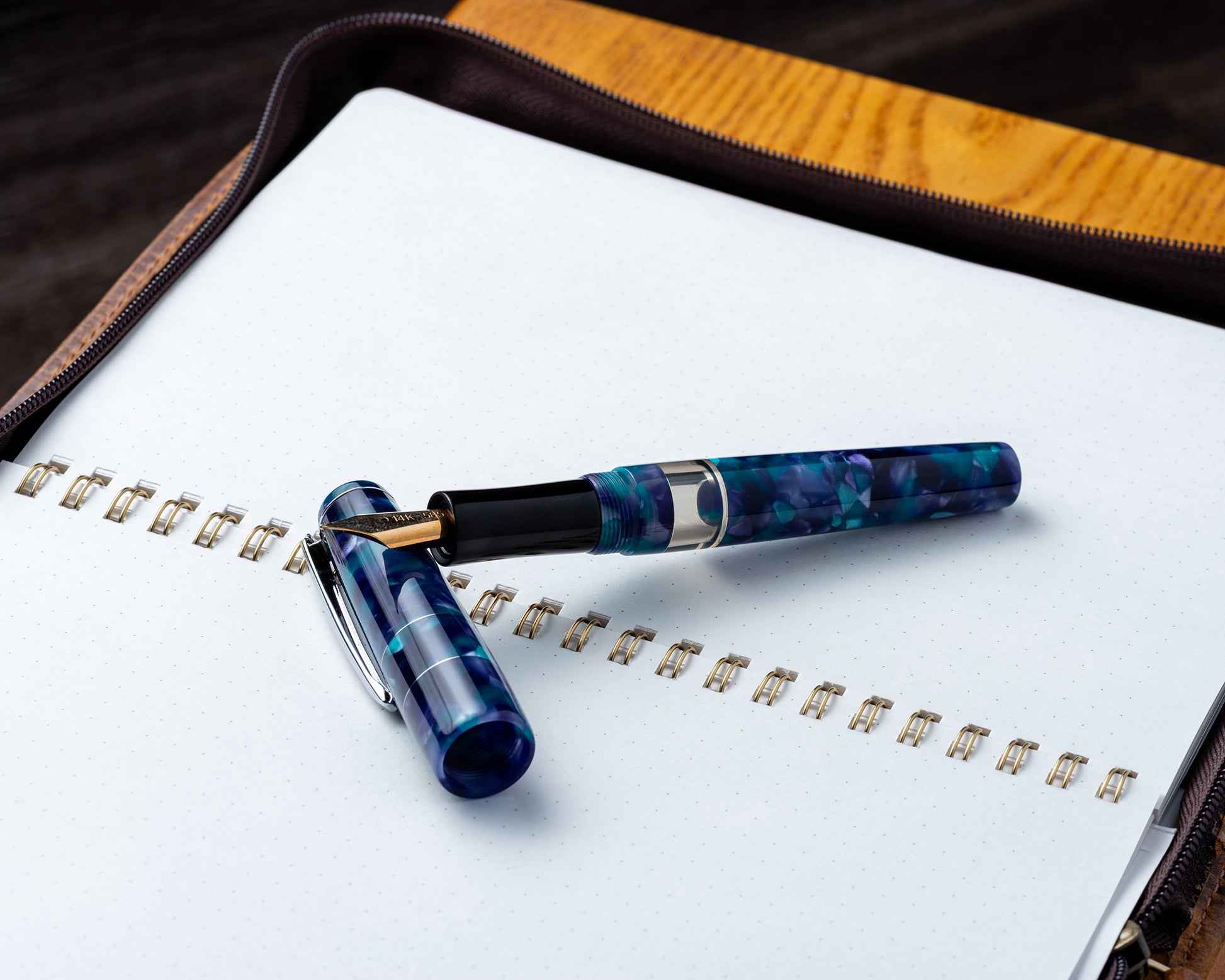 Blue and black pen on a notebook with a wooden surface